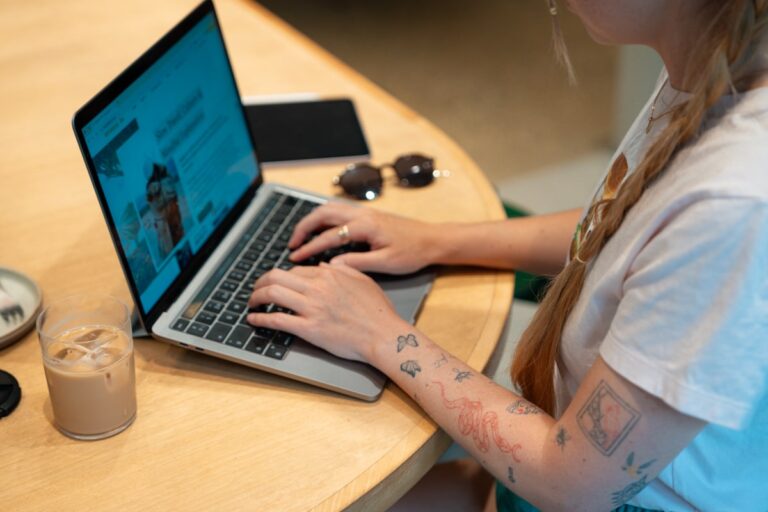 Travel blogger typing on laptop in a cafe.